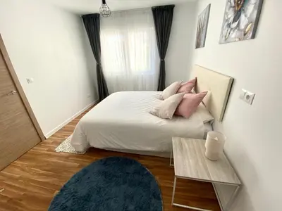 a bedroom with a bed with pink pillows and a table at Apartamentos LAMAROSA -LAS PLAYAS in Burela de Cabo