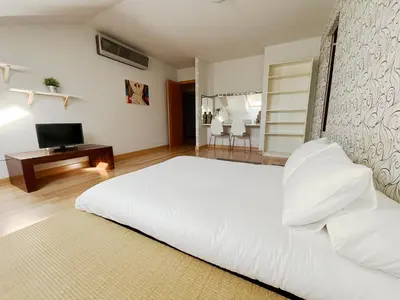 a bedroom with a large white bed and a television at Dúplex Valle del Silencio in Ponferrada