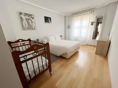 a bedroom with a white bed and a wooden floor at Dúplex Valle del Silencio in Ponferrada