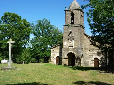 an old stone church with a cross in a field at La Casa de Trefacio in Trefacio