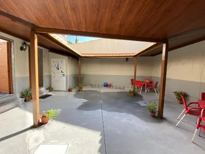 a covered patio with red chairs and a wooden ceiling at Albergue Pereiro in Melide