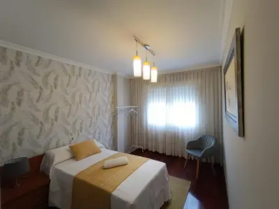 a bedroom with a bed and a chair in it at Apartamento Plaza in Caldas de Reis