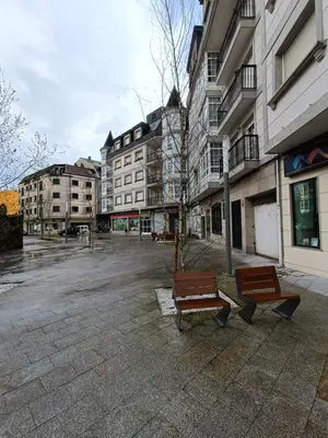two benches sitting in a parking lot next to buildings at Apartamento Plaza in Caldas de Reis