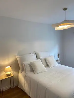 a white bed with pillows and a table with a lamp at Terraza as Travesas in Betanzos