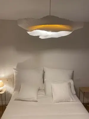 a bed with white pillows and a light above it at Terraza as Travesas in Betanzos