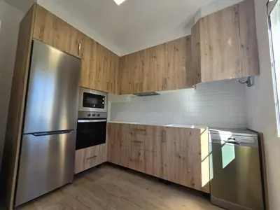 a kitchen with wooden cabinets and a stainless steel refrigerator at CASA DAVID-con cuadras para caballos in Arzúa