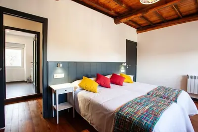 a bedroom with a large bed with red and yellow pillows at Casa do Cesteiro in Santiago de Compostela