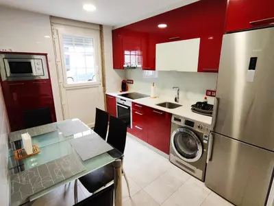 a kitchen with red cabinets and a washing machine at Alojamiento en Santiago de Compostela-Galicia in Santiago de Compostela