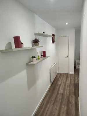 a hallway with white walls and wooden floors and shelves at Alojamiento en Santiago de Compostela-Galicia in Santiago de Compostela