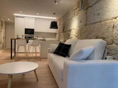 a living room with a white couch and a stone wall at LAS TERRAZAS II Apartamento de lujo frente a la Catedral in Ourense