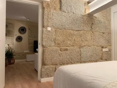 a bedroom with a stone wall next to a bed at LAS TERRAZAS II Apartamento de lujo frente a la Catedral in Ourense
