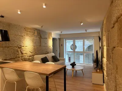 a living room with a table and a stone wall at LAS TERRAZAS II Apartamento de lujo frente a la Catedral in Ourense
