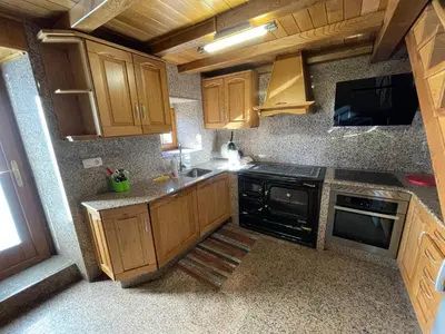a kitchen with wooden cabinets and a black stove at CASA GUIMARAS in Cortes