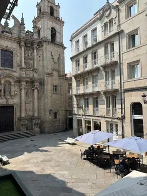 a courtyard with tables and umbrellas in front of a building at LAS TERRAZAS I Lujo frente a la plaza de Santa Eufemia in Ourense