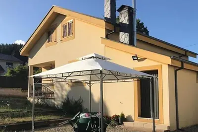 a building with a white umbrella in front of it at El Rincón de la Mimosa in Vega de Espinareda