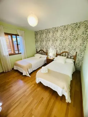 two beds in a room with green walls and wooden floors at El Rincón de la Mimosa in Vega de Espinareda