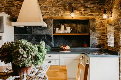 a kitchen with a table with a vase of flowers at Casas de Outeiro in Samos