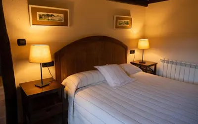 a bedroom with a large white bed with two lamps at Casas de Outeiro in Samos