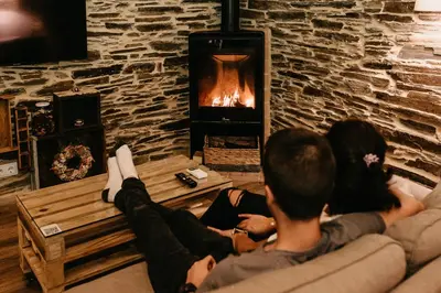 a group of people sitting on a couch in front of a fireplace at Casas de Outeiro in Samos