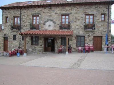 a building with tables and chairs in front of it at Hotel Rural El Molinero de Santa Colomba de Somoza in Santa Colomba de Somoza