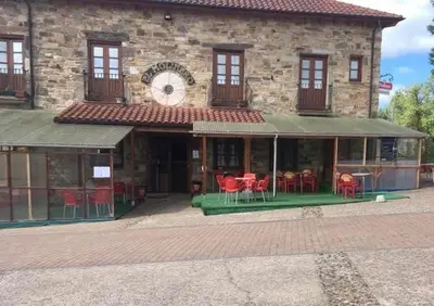 a building with red chairs and a clock on it at Hotel Rural El Molinero de Santa Colomba de Somoza in Santa Colomba de Somoza