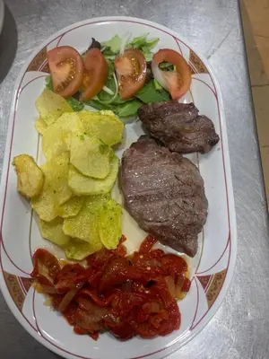 a plate of food with meat and chips and vegetables at Hotel Rural El Molinero de Santa Colomba de Somoza in Santa Colomba de Somoza