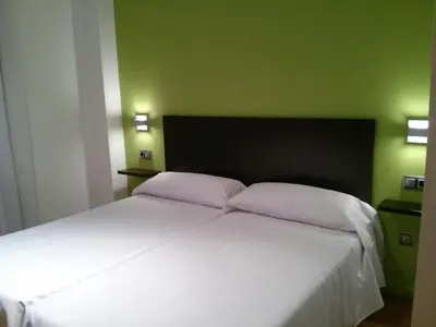 a bedroom with a white bed with a green wall at NRuta Ponferrada in Bembibre