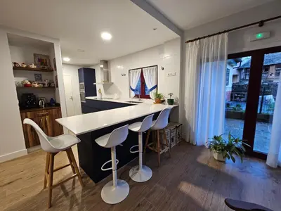 a kitchen with a white counter and stools at La Cochorla in Páramo del Sil