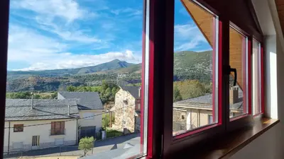 a view from a window of a town with mountains at La Cochorla in Páramo del Sil