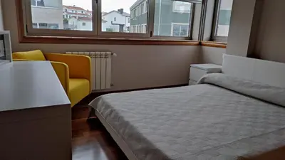 a bedroom with a bed and a chair and a window at Wanderlust Bastiagueiro in Perillo
