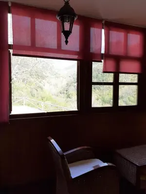 a window with red curtains and a chair in a room at OSO4 in Pola de Somiedo