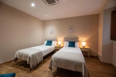two beds in a room with two lamps at EREA apartamentos turísticos in Monforte de Lemos