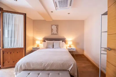 a bedroom with a large bed and two lamps on two tables at SACRA apartamentos turísticos in Monforte de Lemos