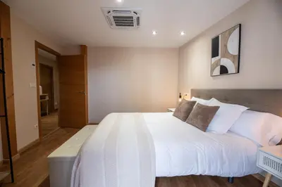 a bedroom with a large white bed in a room at SACRA apartamentos turísticos in Monforte de Lemos