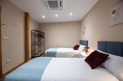 a hotel room with two beds and a fan at SACRA apartamentos turísticos in Monforte de Lemos