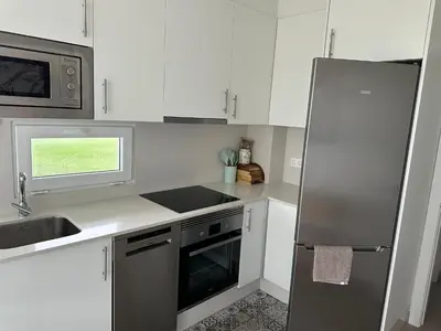 a kitchen with white cabinets and a stainless steel refrigerator at DUNAS DE LLAS in Foz