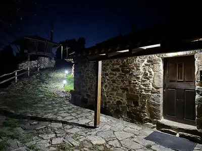 a stone building with a door at night at Ca Manín in Tineo