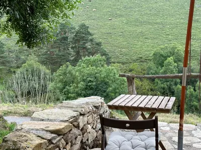 a wooden table and chair sitting next to a stone wall at Ca Manín in Tineo