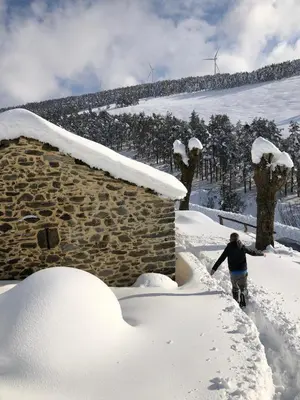 a person walking through snow next to a building at Ca Manín in Tineo