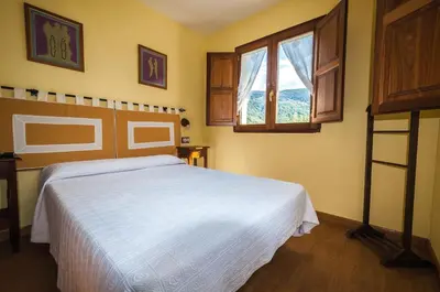 a bedroom with a white bed and a window at Hotel Rural La Bolera in Robles de Laciana