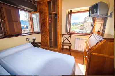 a bedroom with a bed and a window and a tv at Hotel Rural La Bolera in Robles de Laciana