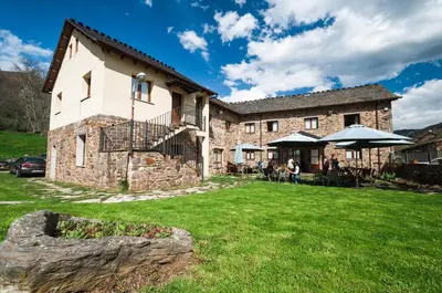 a large stone building with a grass yard at Hotel Rural La Bolera in Robles de Laciana