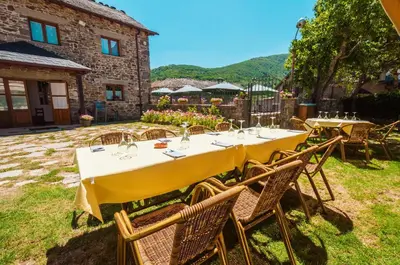 a table with yellow tables and chairs in front of a building at Hotel Rural La Bolera in Robles de Laciana