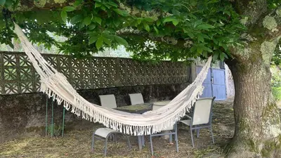 a hammock with chairs and a table under a tree at Casa Camiño do Eume in A Coruña