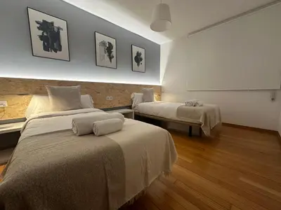 a room with two beds and a white wall at HOME GV35 By Oktheway in Sarria