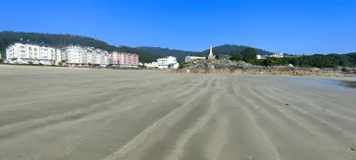 an empty beach with buildings in the background at Alojamientos Viveiro - Playa de Covas I in Viveiro