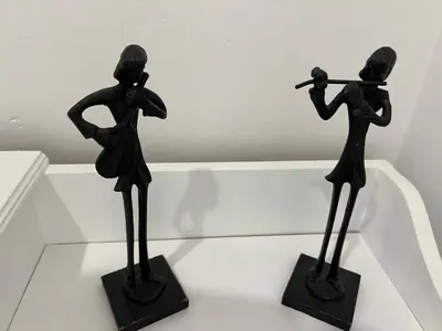 two black statues of a woman playing a baseball at Piso Camino de Santiago in Sarria