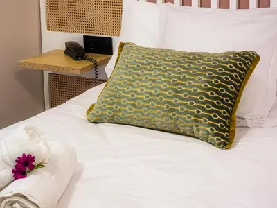 a white bed with a yellow pillow and a table at HOTEL PORTOMARÍN STAR in Portomarin