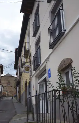 a white building with black balconies on a street at Hostel El Campano in Villafranca del Bierzo