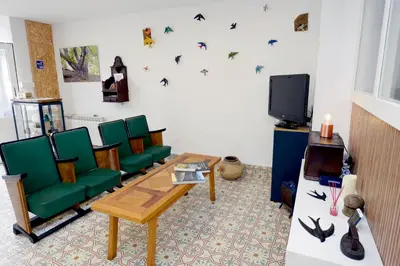 a living room with green chairs and a tv at Hostel El Campano in Villafranca del Bierzo